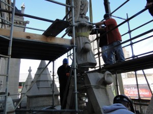 Three commercial masonry contractors securing a stone sculpture